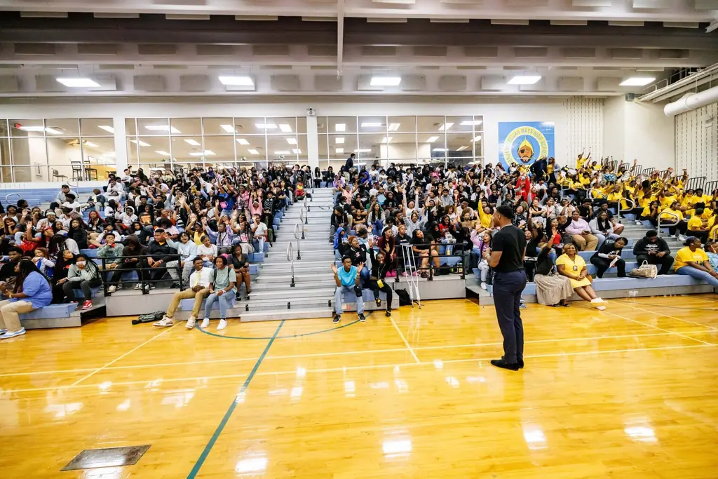 Jovan Paige on the mic in front of a packed high school gym